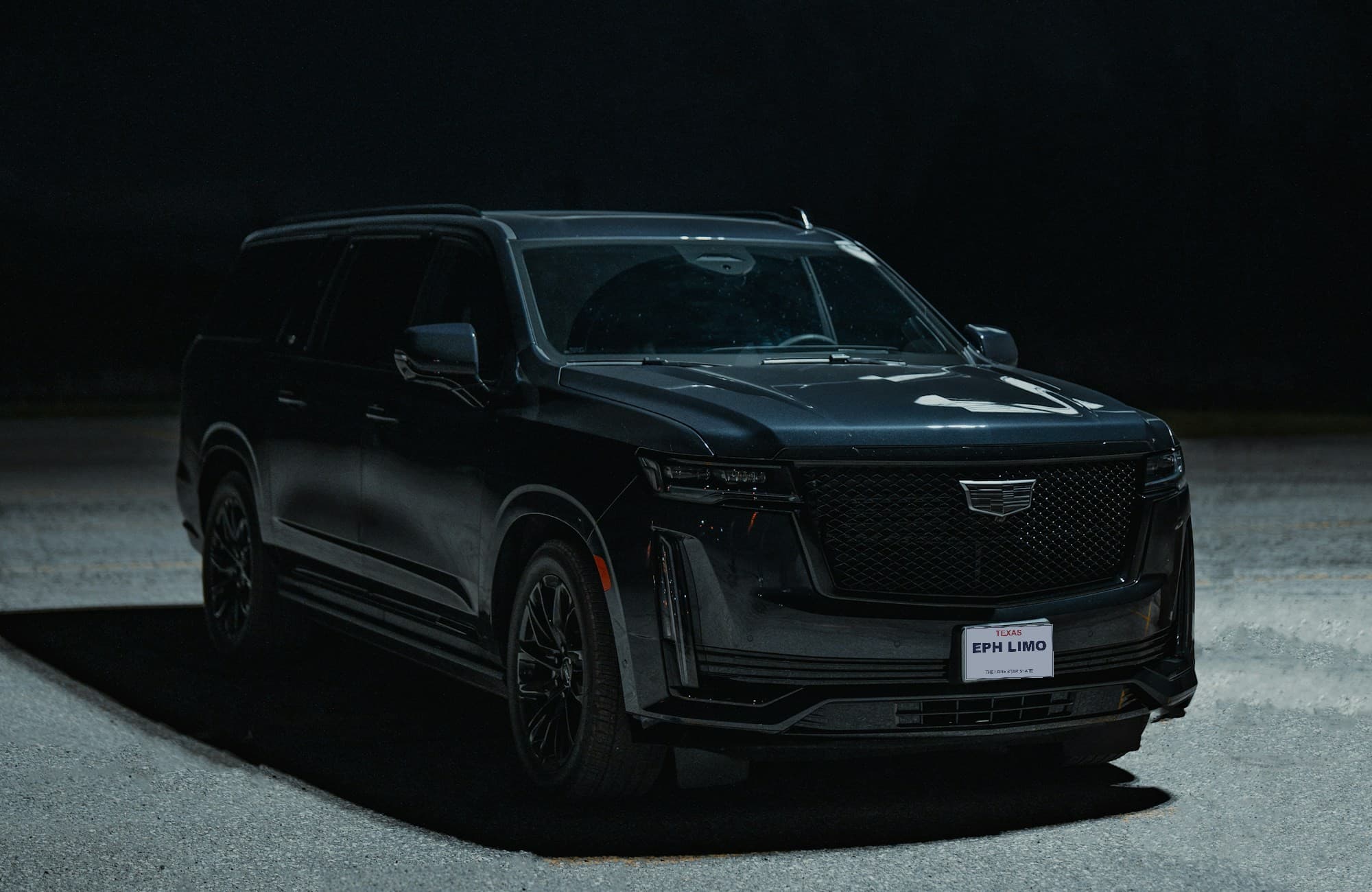 Modern blacked-out Cadillac Escalade with an EPH Limousine Texas plate, spotlit at night